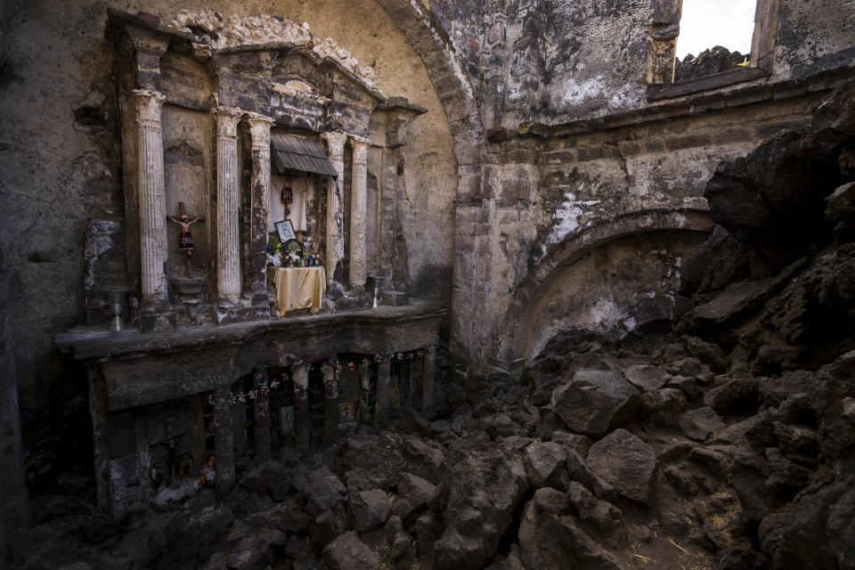 Un altar, adornado con reliquias religiosas, permanece visible dentro de la iglesia enterrada décadas atrás por la lava del volcán Paricutín, en San Juan Parangaricutiro, México, el martes 21 de febrero de 2023. La lava del Paricutín cubrió 18,5 kilómetros cuadrados. Su lento avance permitió a los residentes de las comunidades cercanas trasladarse a otras zonas donadas por el gobierno. (AP Foto/Eduardo Verdugo)