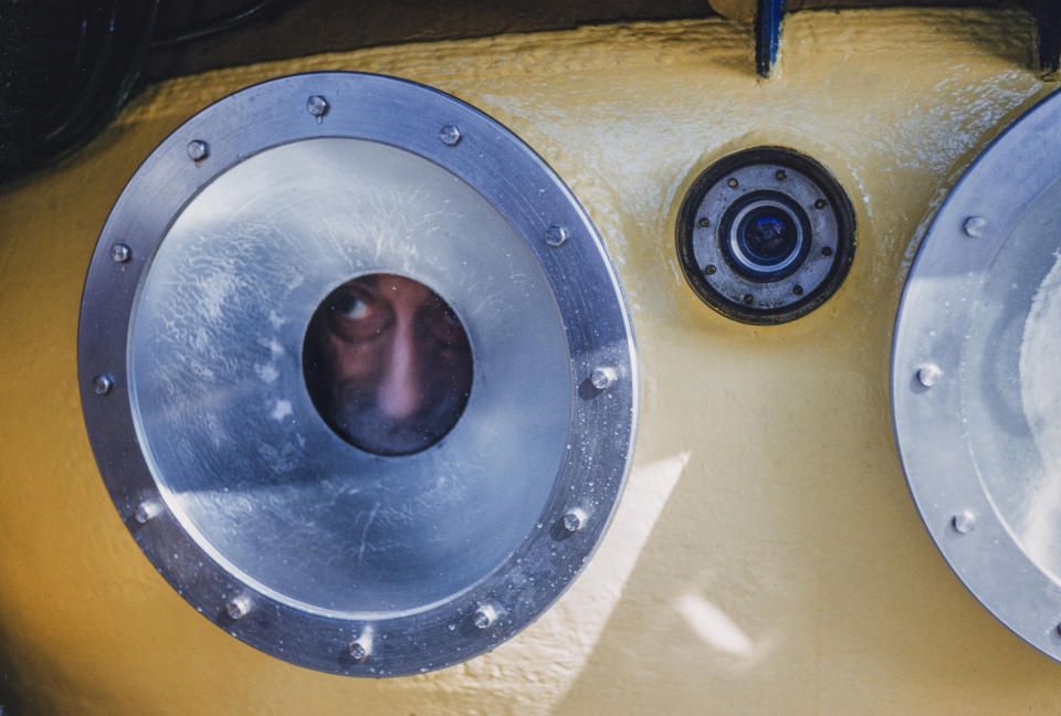 This image released by National Geographic shows Jacques Cousteau peering out of the porthole of a SP-350 Denise diving saucer in 1960, from the documentary “Becoming Cousteau,” opening in theaters Friday. The film attempts to frame the singular Cousteau and his legacy as an early environmental defender of increasingly imperiled waters. (Luis Marden/National Geographic via AP)