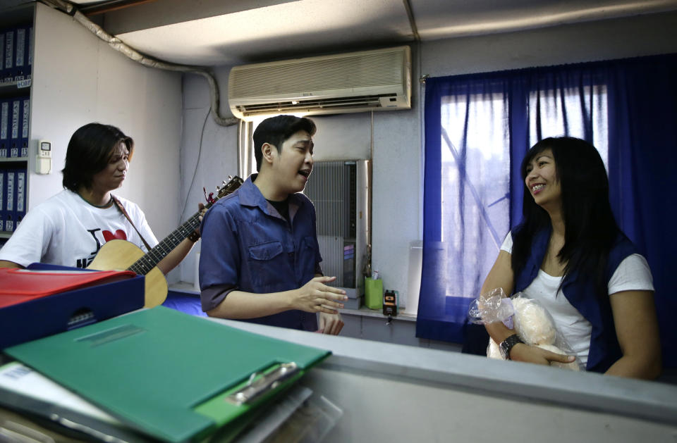 Rose Natividad, right, reacts as a singer, hired by her partner who is working for a cruise liner overseas, serenades her as a surprised Valentine's Day gift to her at her office in Manila, Philippines Thursday Feb. 14, 2013. The unique surprise serenade service, which includes love songs, a cuddly teddy bear, and a video recording of the romance-by-proxy event that is shipped to the client abroad, is played out in restaurants, offices and homes across the Philippines on Valentine's Day. (AP Photo/Bullit Marquez)