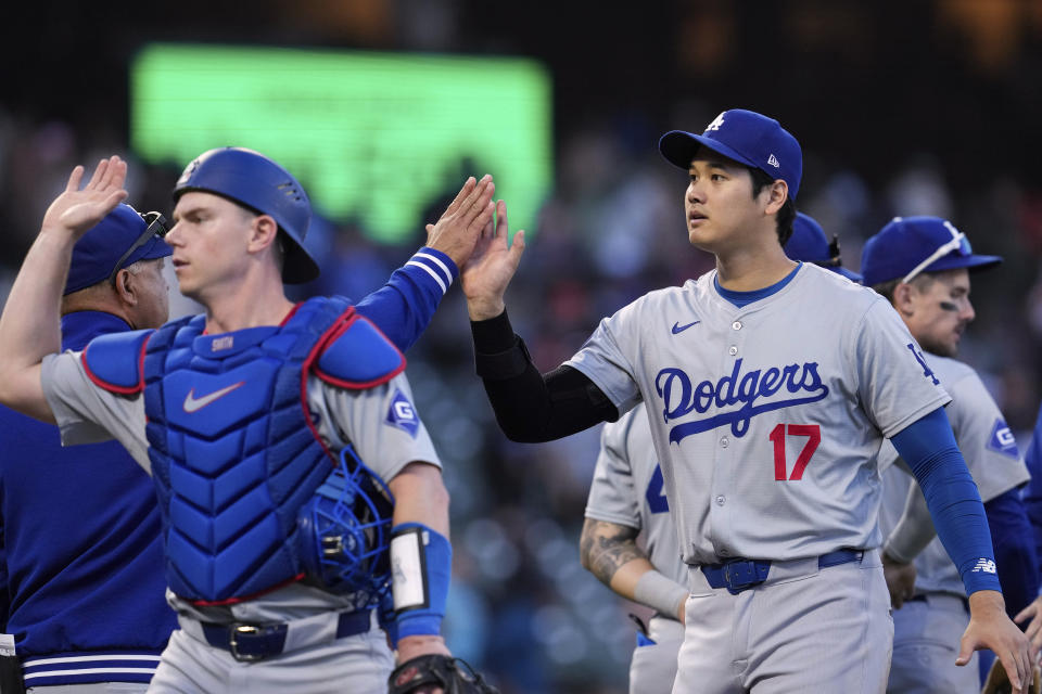 Los Angeles Dodgers' Shohei Ohtani, right, celebrates with manager Dave Roberts, back left, after the team's victory over the San Francisco Giants in a baseball game Saturday, June 29, 2024, in San Francisco. (AP Photo/Godofredo A. Vásquez)