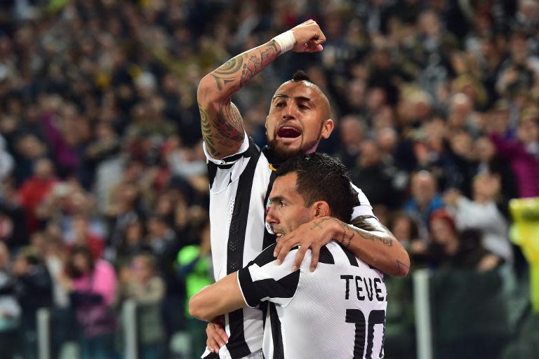 Juventus' forward from Argentina Carlos Tevez (R) celebrates after scoring with teammate Arturo Vidal during their Italian Serie A football match against Lazio in Turin, Italy, on April 18, 2015