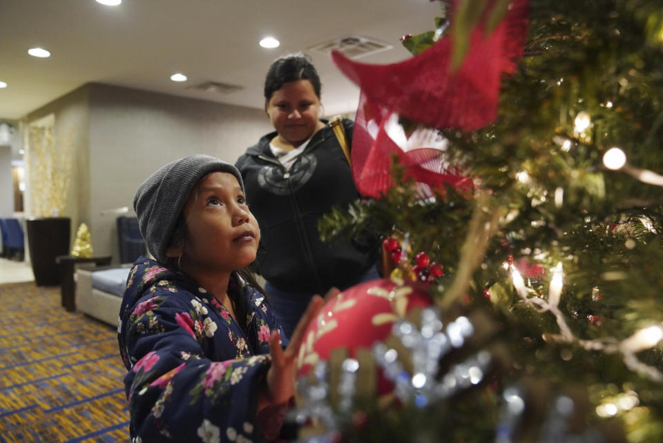 A 7-year-old asylum-seeker looks at a Christmas tree at the hotel where she and her mother, Isabel, 21, rear, are spending the night after being processed at the Port of Entry in Brownsville, Texas, Tuesday, Dec. 17, 2019. The girl who is unable to contain her own waste due to a congenital illness and who had been refused entry to the United States three times has finally been allowed into the country. (AP Photo/Veronica G. Cardenas)