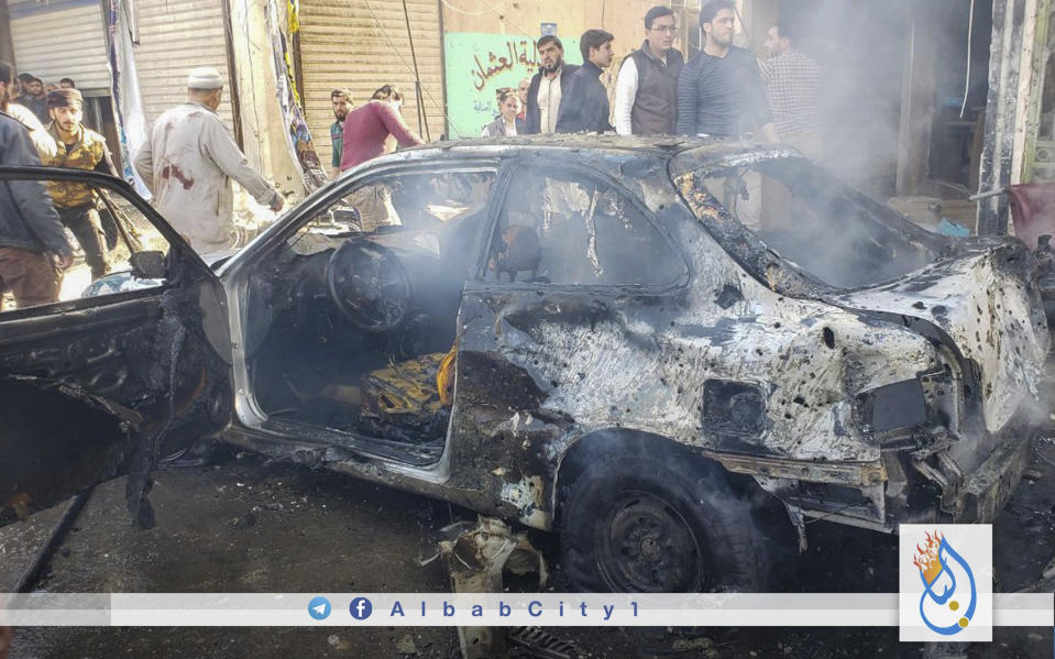 This photo provided by the Syrian anti-government activist group Albab City, which has been authenticated based on its contents and other AP reporting, people check the aftermath of a car bomb exploded in the city of al-Bab, northern Syria, Saturday, Nov. 16, 2019. A car bomb exploded Saturday in a northern Syrian town controlled by Turkey-backed opposition fighters, killing at least 18 people and wounding several others, Syrian opposition activists and Turkey's Defense Ministry said. (Albab City via AP)