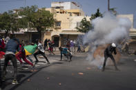 Demonstrators run after rioT police fired a stone grenade during protests against the arrest of opposition leader and former presidential candidate Ousmane Sonko, Senegal, Monday, March 8, 2021. Senegalese authorities have freed opposition leader Ousmane Sonko while he awaits trial on charges of rape and making death threats. The case already has sparked deadly protests threatening to erode Senegal's reputation as one of West Africa’s most stable democracies. (AP Photo/Leo Correa)