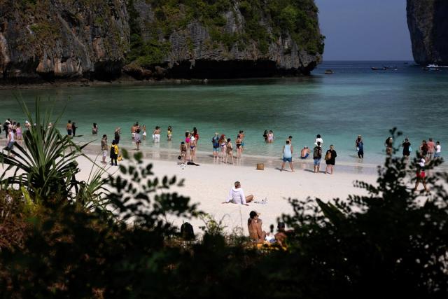 Tourists enjoy the beach where swimming is forbidden and people are only allowed to enter water up to their knees (Reuters)