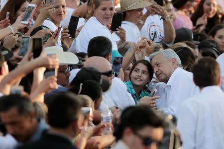 Mexico's President Andres Manuel Lopez Obrador poses for a photo with a child during his arrival to an event in Badiraguato, in the Mexican state of Sinaloa, Mexico February 15, 2019. REUTERS/Daniel Becerril