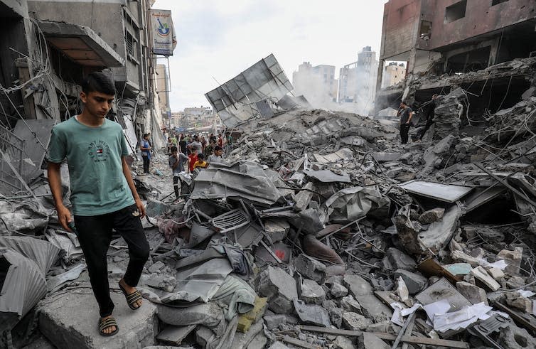 A young man stands in the rubble of the Khan Yunis municipality building after an Israeli air strike, building in Gaza, October 2023.