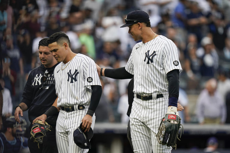 New York Yankees' Aaron Judge, right, checks on Gio Urshela, center, after he was hurt running into the Tampa Bay Rays dugout chasing a ball hit by Austin Meadows for an out during the sixth inning of a baseball game Sunday, Oct. 3, 2021, in New York. (AP Photo/Frank Franklin II)