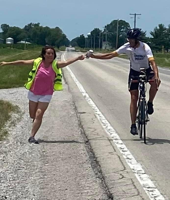 Nikki Crooks hands off nutrition to her husband, Les Crooks, of Mishawaka, as he races in the Race Across America in June 2022.