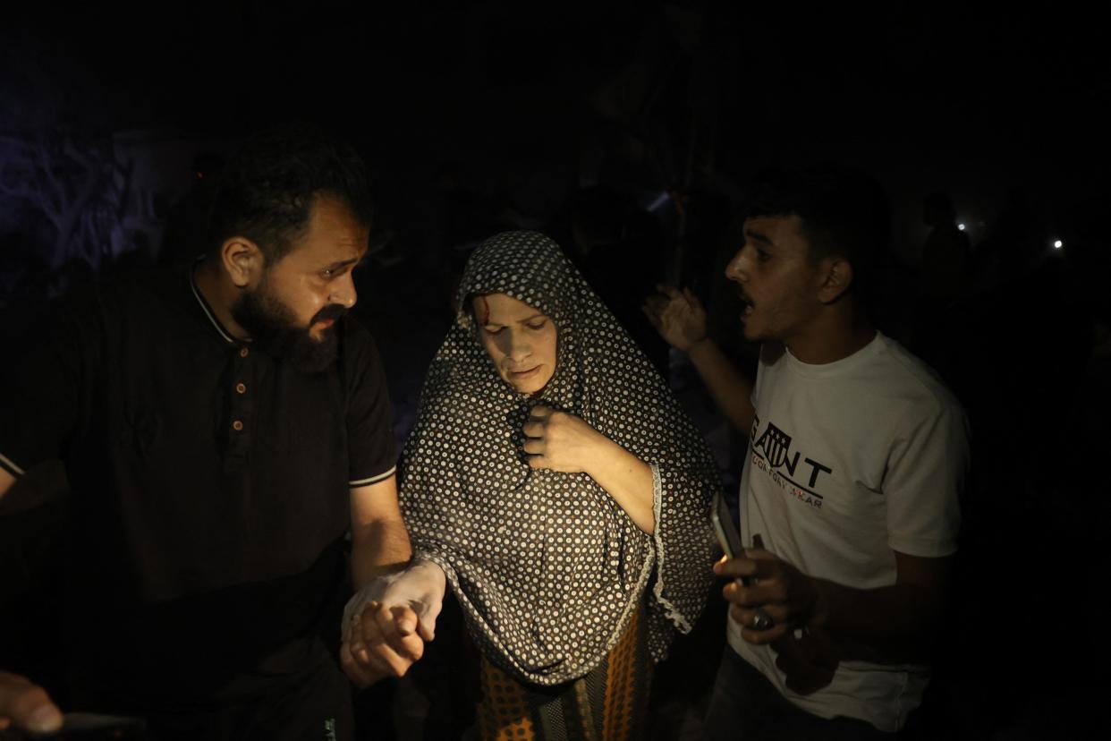 Palestinians help evacuate a woman from the area where a residential building that was hit by Israeli bombardment in Rafah on Tuesday.