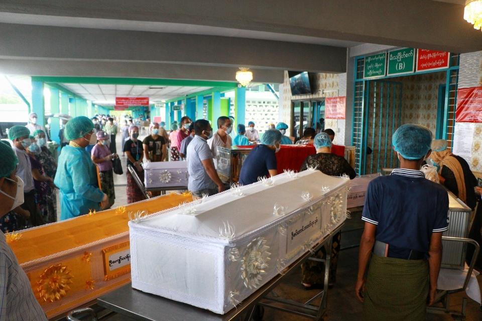 People wearing face masks wait while caskets with bodies are queued outside a crematorium at the Yay Way cemetery in Yangon, Myanmar, Wednesday July 14, 2021. The number of people dying in Myanmar's biggest city, Yangon, which is facing a coronavirus surge and a shortage of oxygen to treat patients, has been climbing so quickly that charity groups said Wednesday they are almost overwhelmed. (AP Photo)