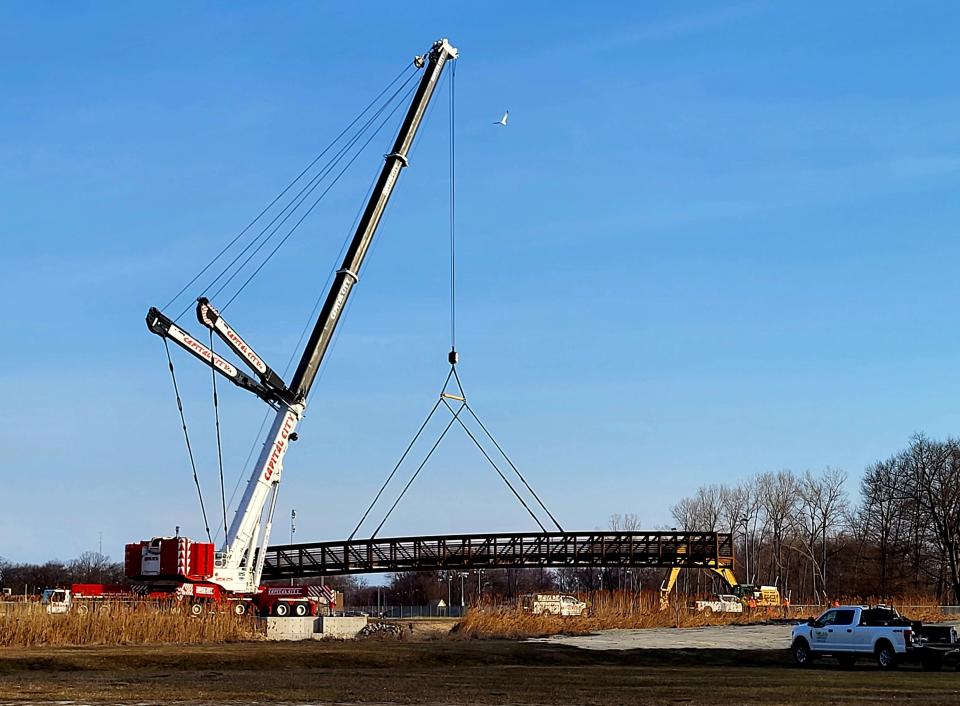 The massive Black River Canal truss bridge is lifted over the watercourse into place on Tuesday, March 21, 2023. It was the first major step in completing a $1.4 million pathway over the canal, as well as a spot in the Bridge to Bay Trail.