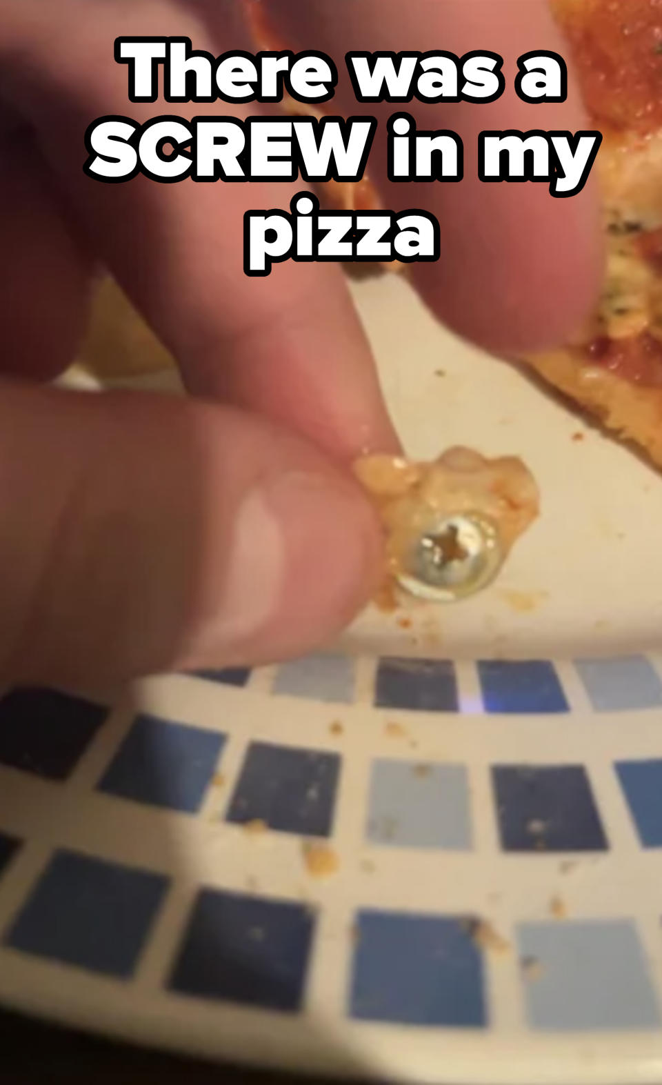 Someone holding a screw they found in their pizza