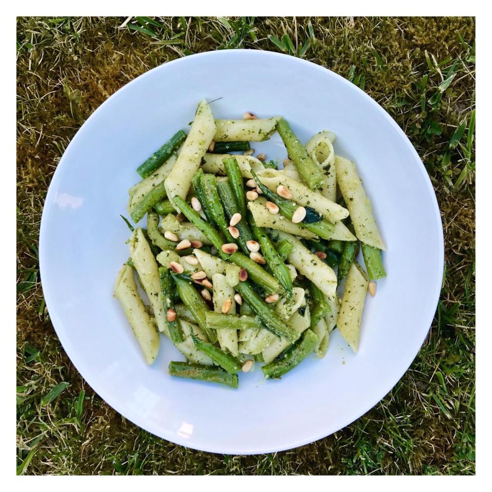 <p>Pour 4 personnes </p><p> 1 petite pomme de terre<br> 300 g de haricots verts<br> 250 g de pâtes (idéalement des penne)<br> <b>Le pesto</b><br> 25 g de pignons de pin<br> 20 g de parmesan râpé<br> sel<br> poivre moulu<br> 1 à 3 gousses d’ail<br> 3 ou 4 tiges de basilic<br>10 cl d’huile d’olive</p><p> Pelez une petite pomme de terre et coupez-la en dés d’un centimètre de côté. Équeutez 300 g de haricots verts (seulement côté tige, cela suffit), puis rincez-les avant de les couper en 2 ou 3.<br> Plongez 250 g de pâtes (idéalement des penne) et les dés de pommes de terre dans une grande casserole d’eau bouillante salée. Laissez cuire le tout une dizaine de minutes jusqu’à é que les pâtes soient cuites al Dente.<br> Mixez 25 g de pignons de pin, 20 g de parmesan râpé, une pincée de sel, du poivre moulu, 1 a 3 gousses d’ail pelées et dégermées (cela dépend de votre amour pour l’ail : un peu, beaucoup, passionnément...), les feuilles de 3 ou 4 tiges de basilic et 10 cl d’huile d’olive.<br> 5 minutes avant la fin de la cuisson des pâtes, ajoutez les tronçons de haricots verts à la casserole de pâtes. Laissez cuire. Dans une poêle à feu doux, faites griller 25 g de pignons de pin.<br> Quand les pâtes sont cuites al dente, coupez le feu, réservez 2 louches d’eau de cuisson et égouttez le tout (pâtes + dés de pomme de terre + haricots verts). Reversez le tout dans la casserole, ajoutez le pesto, un peu d’huile d’olive, salez et poivrez.<br>Servez les pâtes chaudes ou tièdes avec du parmesan râpé et les pignons de pin grillés.</p><p> Recette de Danièle Gerkens<br> <a href="https://www.instagram.com/danielegerkens/?hl=fr" rel="nofollow noopener" target="_blank" data-ylk="slk:@danielegerkens;elm:context_link;itc:0;sec:content-canvas" class="link ">@danielegerkens</a></p><br>