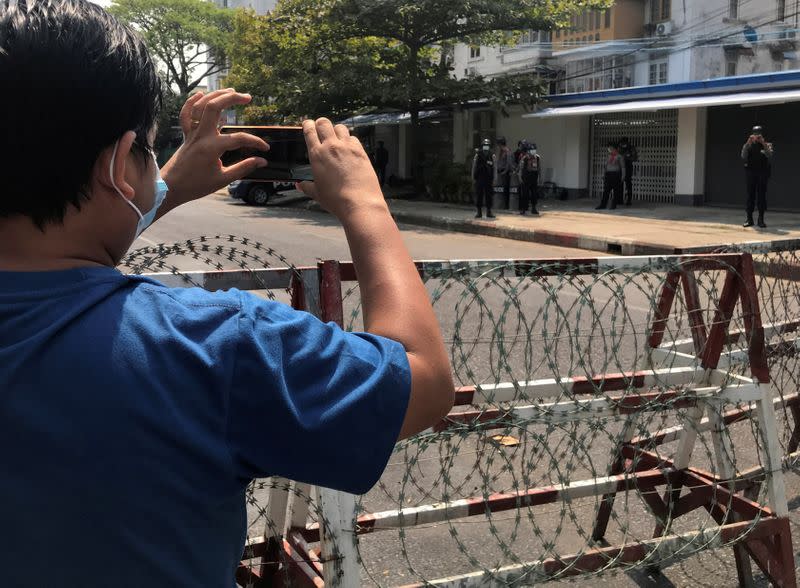 A journalist and a police officer take pictures of each other as people protest against the military coup in Yangon, Myanmar