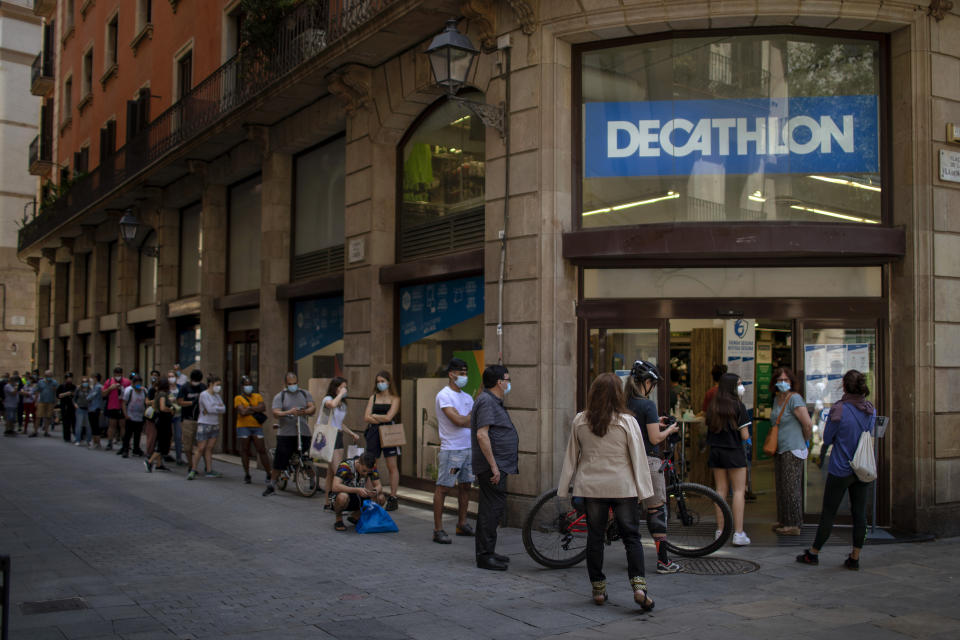 Customers queue outside a sportswear and equipment store during the coronavirus outbreak in Barcelona, Spain, Thursday, June 4, 2020. (AP Photo/Emilio Morenatti)