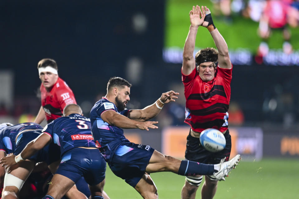 Ryan Louwrens of the Melbourne Rebels kicks the ball as Scott Barrett of the Crusaders attempts to charge it down during their Super Rugby match in Christchurch, New Zealand, Friday, April 26, 2024. (John Davidson/Photosport/AAP Image/ via AP)