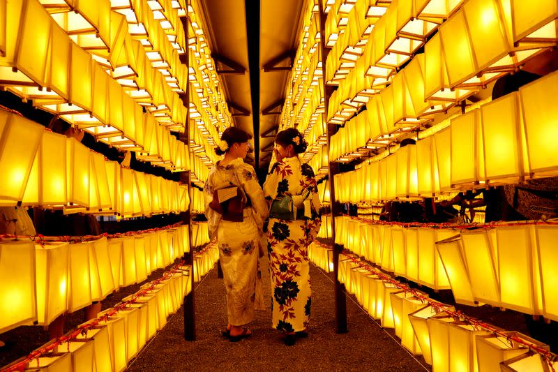 FILE PHOTO: Women in yukatas, or casual summer kimonos, pose to take photos between paper lanterns during the annual Mitama Festival at Yasukuni Shrine in Tokyo, Japan