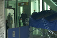 Passengers arriving on the flight from Singapore are processed by staff in protective clothings and directed towards a covered walkway to a separate exit from the Airport terminal in Wuhan in central China's Hubei province on Thursday, Jan. 14, 2021. Chinese state media reported that a WHO team arrived in Wuhan, China, on Thursday to research the origins of the coronavirus.(AP Photo/Ng Han Guan)