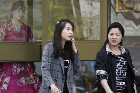 A woman wearing traditional costume waits for customers behind the doors of a North Korean restaurant in Beijing, China, April 12, 2016. REUTERS/Damir Sagolj