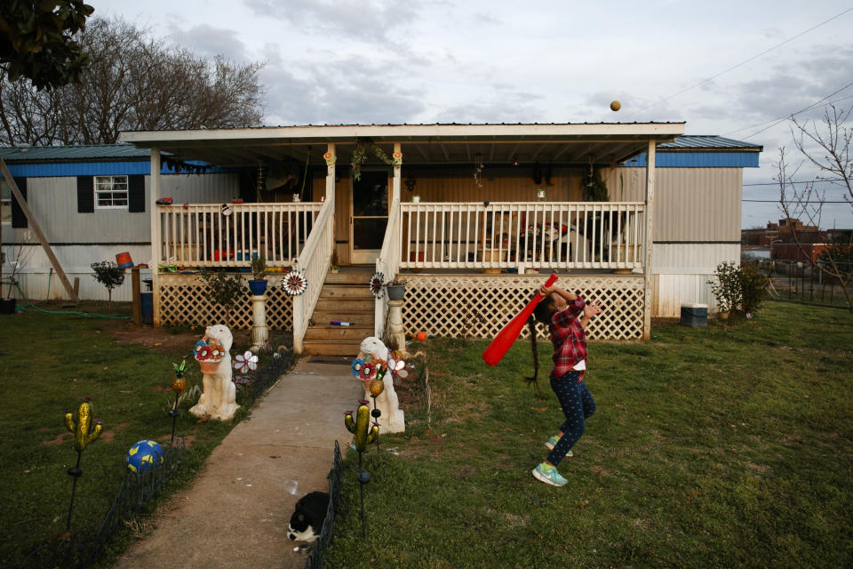 Dulce, de 6 años, juega en el jardín de la casa familiar en un parque de casas rodantes junto a las vías del tren, en Burlington, Carolina del Norte, el lunes 9 de marzo de 2020. (AP Foto/Jacquelyn Martin)