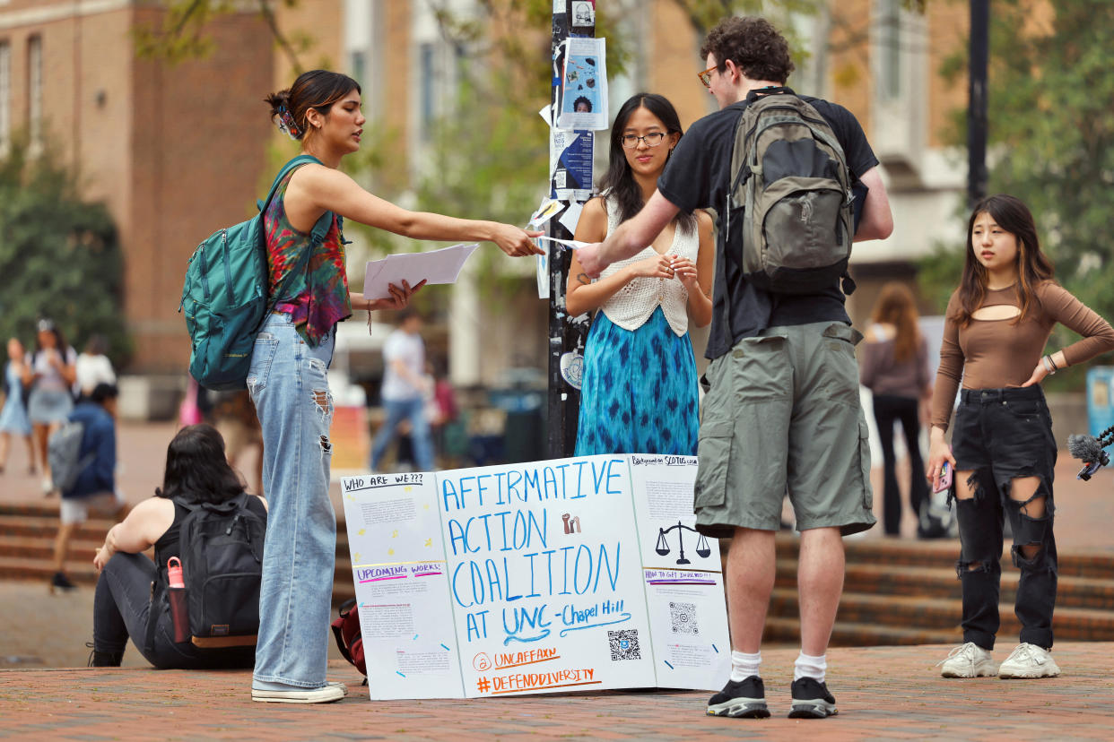A student activist with the Affirmative Action Coalition hands a flier to a passerby on campus.