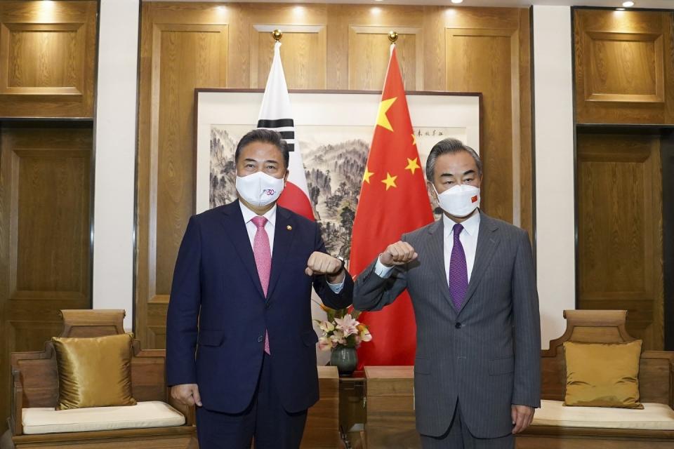 In this photo provided by South Korea Foreign Ministry, South Korean Foreign Minister Park Jin, left, bumps elbows with his Chinese counterpart Wang Yi prior to their meeting in Qingdao, China, Tuesday, Aug. 9, 2022. (South Korea Foreign Ministry via AP)