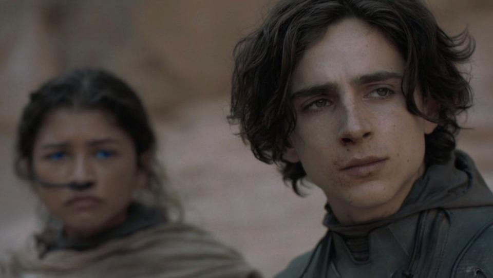 Paul Atreides in his stillsuit in front of Chani in hers out in the desert in Dune: Part One