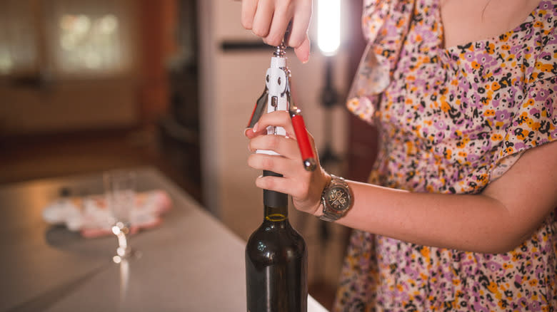 Person opening bottle of wine