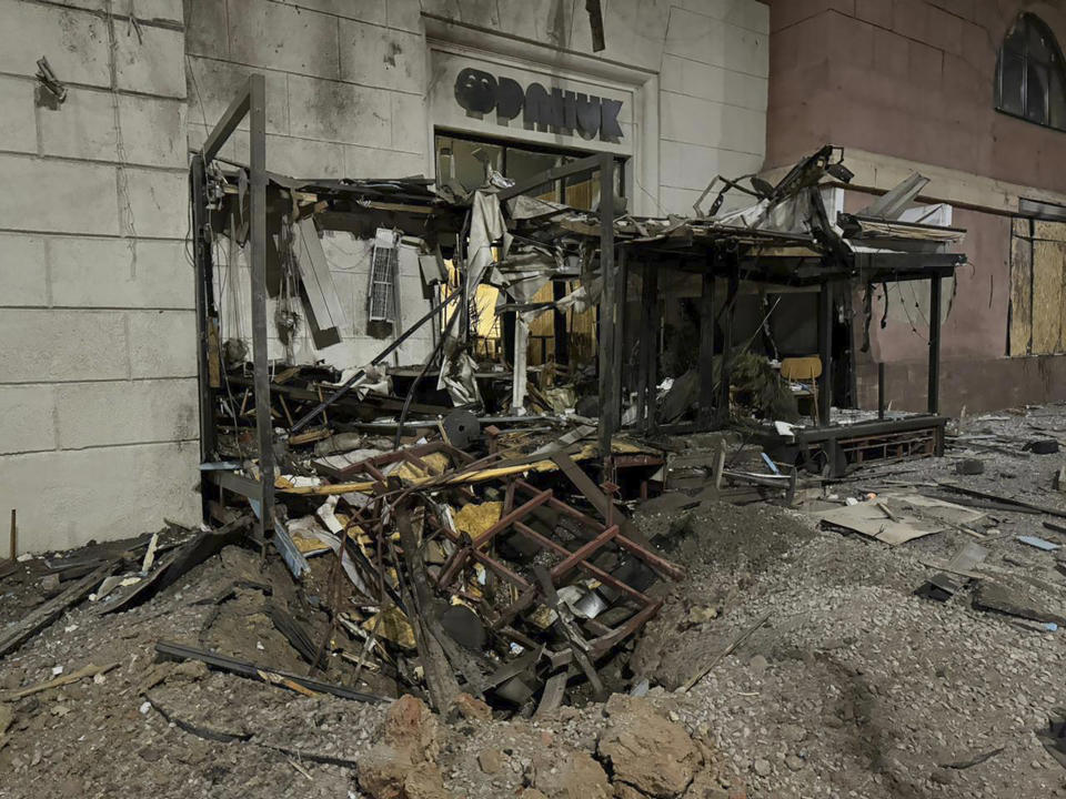 In this photo provided by Kharkiv Regional Administration, a missile crater in front of a store in the city center is seen after Russia's missile attack in Kharkiv, Ukraine, Sunday, Dec. 31, 2023. (Kharkiv Regional Administration via AP)