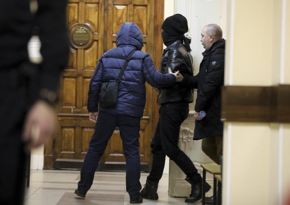 One of two terrorism suspects is escorted by the Federal Security Service (FSB), the main KGB successor agency, to a courtroom in St. Petersburg, Russia, Monday, Dec. 30, 2019. A court in St. Petersburg has ordered the detention of two Russian men who were arrested on a tip provided by the U.S. and are suspected of plotting unspecified terrorist attacks in the city during the New Year holidays. (David Frenkel/Kommersant Publishing House via AP)