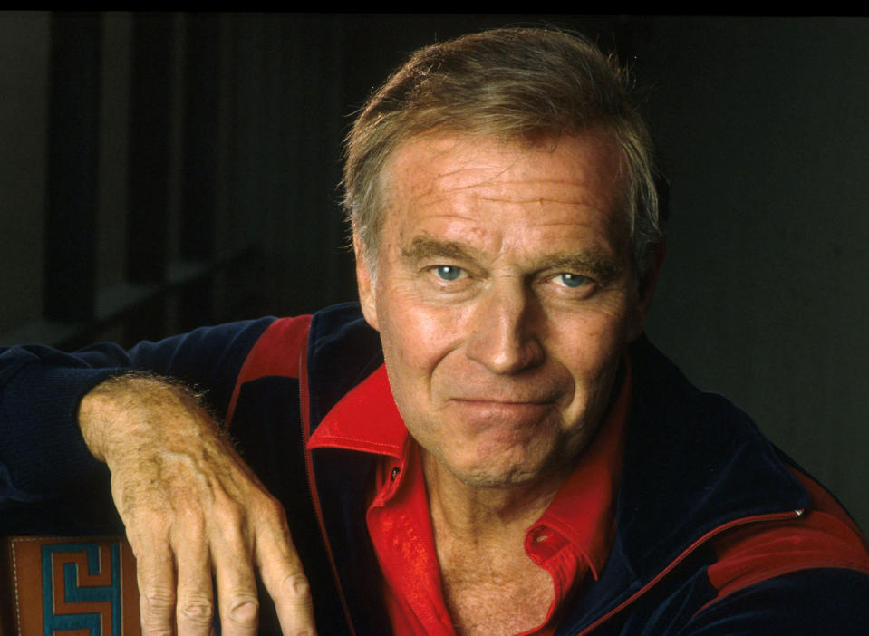 An older man with short hair, wearing a collared shirt and jacket, smiling at the camera