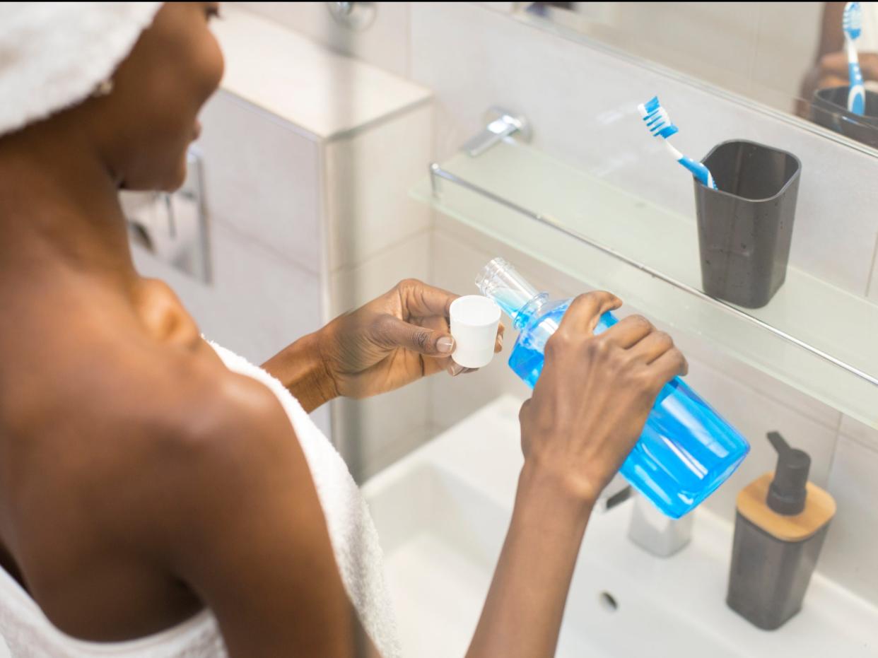 A person uses mouthwash after brushing their teeth (Getty Images)