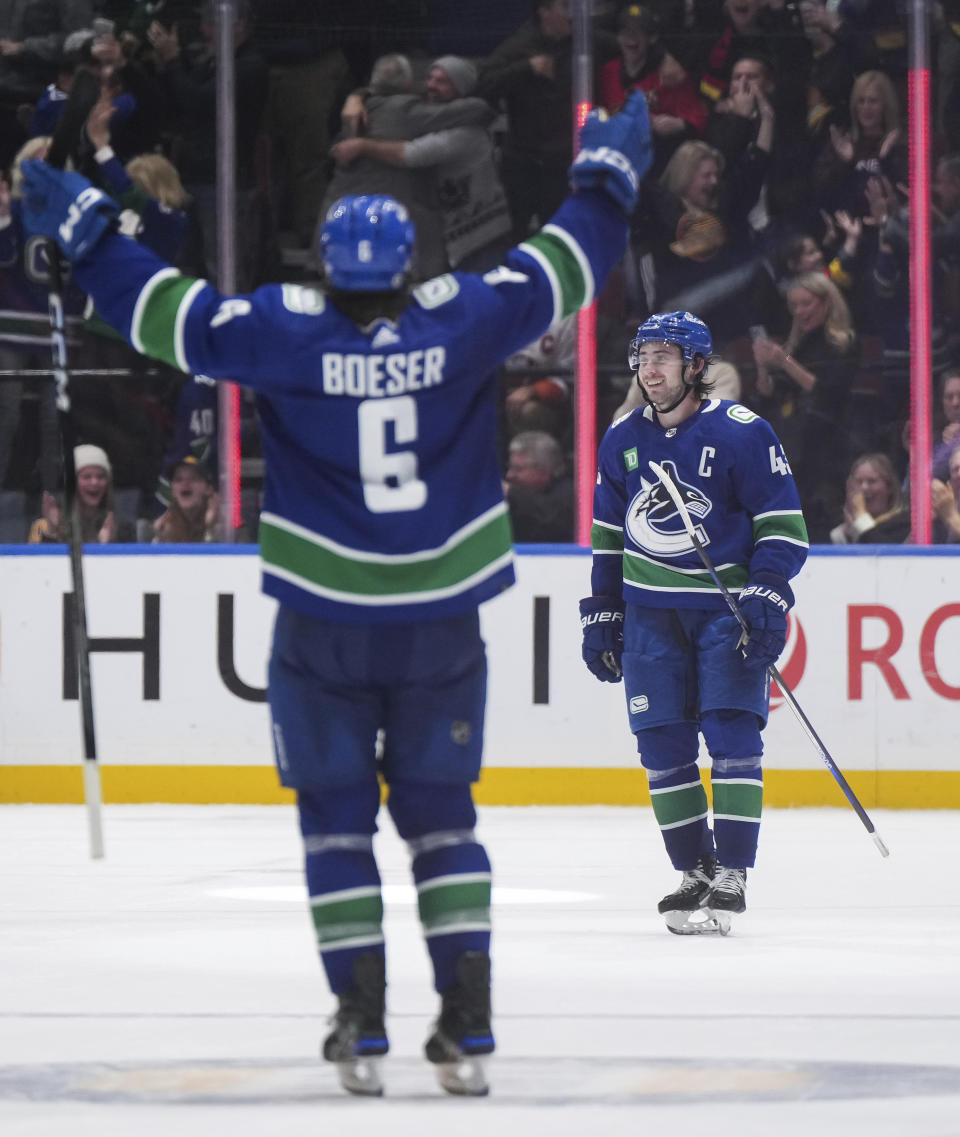 Vancouver Canucks' Quinn Hughes, rear, and Brock Boeser celebrate Hughes' overtime goal against the New York Islanders during an NHL hockey game Wednesday, Nov. 15, 2023, in Vancouver, British Columbia. (Darryl Dyck/The Canadian Press via AP)