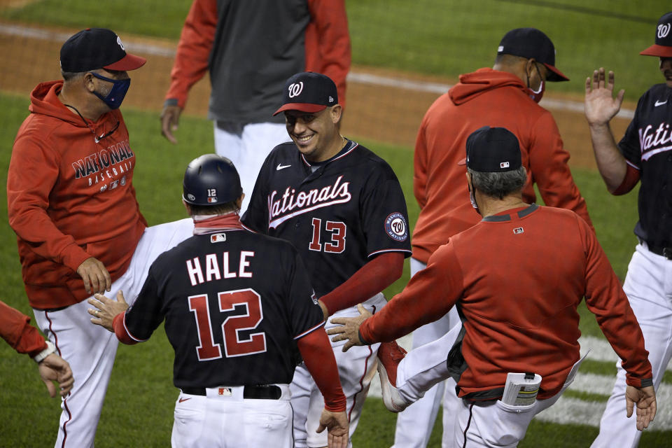 Washington Nationals' Asdrubal Cabrera (13) celebrates with third base coach Chip Hale (12) and others after a baseball game against the Philadelphia Phillies, Monday, Sept. 21, 2020, in Washington. (AP Photo/Nick Wass)