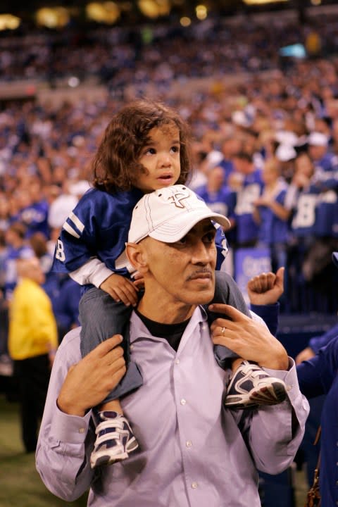 Former Indianapolis Colts coach Tony Dungy holds his son Justin on his shoulders during the first half of an NFL divisional football playoff game between the Colts and Baltimore Ravens, Saturday, Jan. 16, 2010, in Indianapolis. (AP Photo/Mark Duncan)