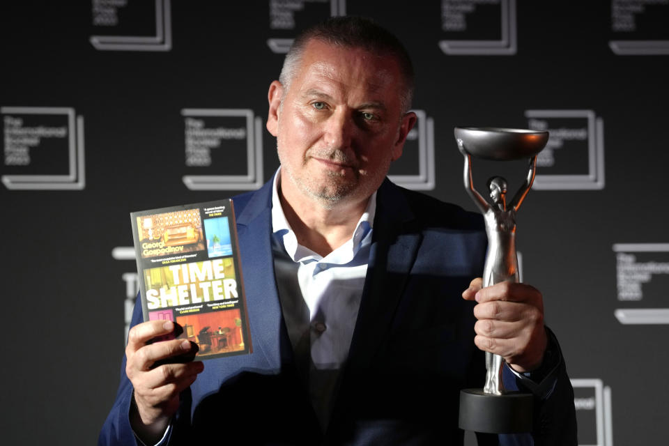 Bulgarian writer Georgi Gospodinov holds up his book "Time Shelter" translated from Bulgarian by Angela Rodel after winning The International Booker Prize 2023, in London, Tuesday, May 23, 2023. (AP Photo/Kirsty Wigglesworth)