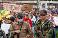 People hold signs while others carry weapons during a protest against the coronavirus shutdown in front of State Capitol in Madison, Wisconsin, on April 24, 2020. - Gyms, hair salons and tattoo parlors had a green light to reopen in the US state of Georgia on Friday as the death toll from the coronavirus pandemic soared past 50,000 in the U.S. (Photo by KAMIL KRZACZYNSKI/AFP via Getty Images)