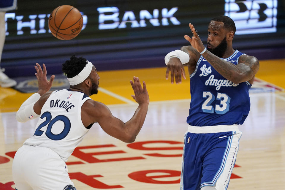 Los Angeles Lakers forward LeBron James, right, passes the ball over Minnesota Timberwolves forward Josh Okogie during the first half of an NBA basketball game Tuesday, March 16, 2021, in Los Angeles. (AP Photo/Mark J. Terrill)