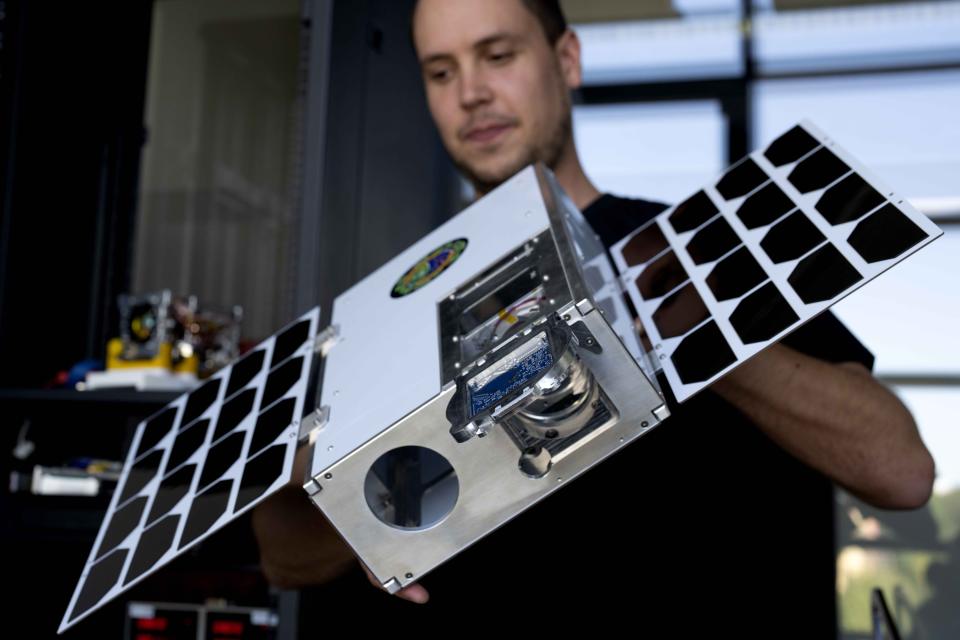 An employee of the German startup OroraTech lifts a satellite enclosure in Munich, Germany, Thursday, Sept. 13, 2023. The Munich-based company analyzes satellite images with artificial intelligence. The AI also takes into account factors like the type and condition of vegetation in the area and humidity levels, to detect and identify those flareups that have the potential to spawn devastating megafires. (AP Photo/Matthias Schrader)