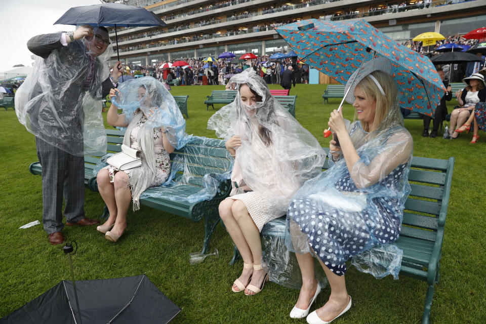 Racegoers shelter from the rain with their umbrellas and plastic raincoats on the second day of the annual Royal Ascot horse race meeting in Ascot, England, Wednesday, June 19, 2019. (AP Photo/Alastair Grant)