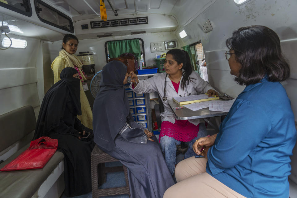 Doctor Barira Chaudhary, second right, from Myna Mahila Foundation, a local women's organization, examines a patient inside a mobile clinic at a slum in Mumbai, India, Feb. 1, 2024. The organization is training a chatbot powered by artificial intelligence to answer women's questions about sexual reproductive health. The chatbot, currently a pilot project, represents what many hope will be part of the impact of AI on health care around the globe. (AP Photo/Rafiq Maqbool)