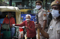 Indian policemen wearing masks stand at a traffic intersection as an elderly man pushes his cycle through a traffic jam in New Delhi, India, Monday, Sept. 21, 2020. The nation of 1.3 billion people is expected to become the coronavirus pandemic's worst-hit country within weeks, surpassing the United States. (AP Photo/Manish Swarup)