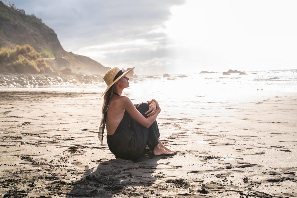 a woman sitting on the sand on a quiet beach