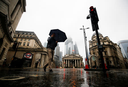 People walk through the financial district during rainy weather in London, Britain, September 23, 2018. Picture taken September 23, 2018. REUTERS/Henry Nicholls