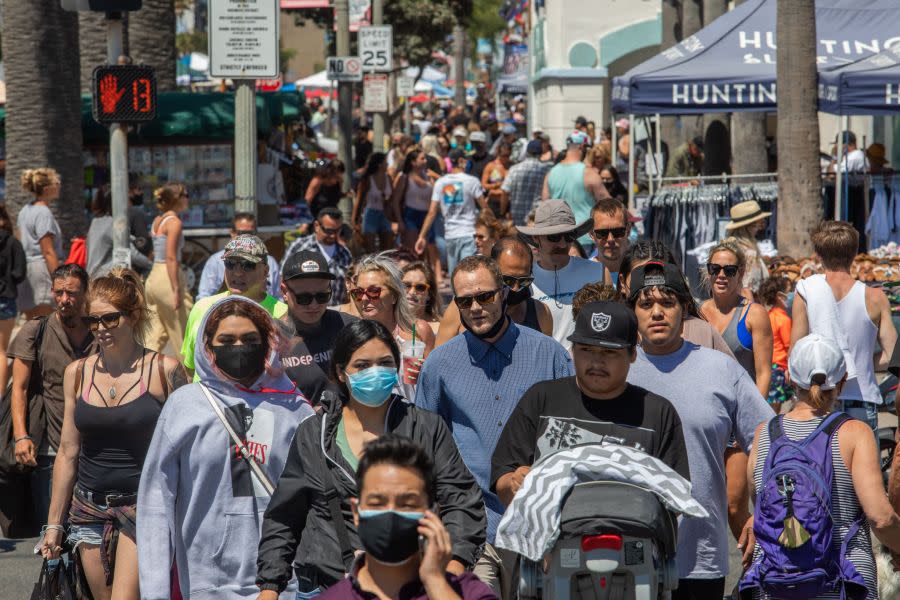 People cross the street in Huntington Beach on July 19, 2020, amid the coronavirus pandemic. (Apu Gomes / AFP / Getty Images)