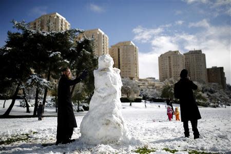 An ultra-Orthodox Jewish man builds a snowman in Jerusalem December 12, 2013. REUTERS/Amir Cohen