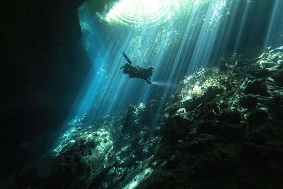 Cave diving instructor Peter Broger explores the "Jardin del Eden," or Eden's Garden cenote as rays of sunlight slice through the water near Tulum, Mexico, Wednesday, Feb. 28, 2024. These glowing sinkhole lakes, known as cenotes, are a part of one of Mexico's natural wonders: A fragile system of thousands of subterranean caverns, rivers, and lakes that wind beneath Mexico's southern Yucatan peninsula.(AP Photo/Rodrigo Abd)