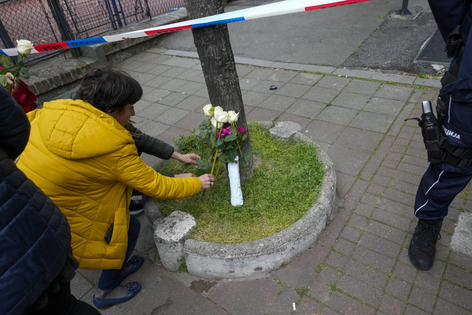 Women lay flowers for victims near the Vladislav Ribnikar school in Belgrade, Serbia, Wednesday, May 3, 2023. A 13-year-old who opened fire Wednesday at his school in Serbia's capital drew sketches of classrooms and wrote a list of people he intended to target in a meticulously planned attack, police said. (AP Photo/Darko Vojinovic)