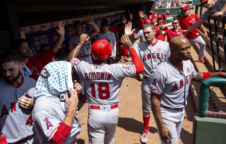 Los Angeles Angels' Brian Goodwin (18) is congratulated in the dugout after scoring on a two run home run by Luis Rengifo during the fifth inning of the first baseball game of a doubleheader Tuesday, Aug. 20, 2019, in Arlington, Texas. Los Angeles won 5-1. (AP Photo/Jeffrey McWhorter)